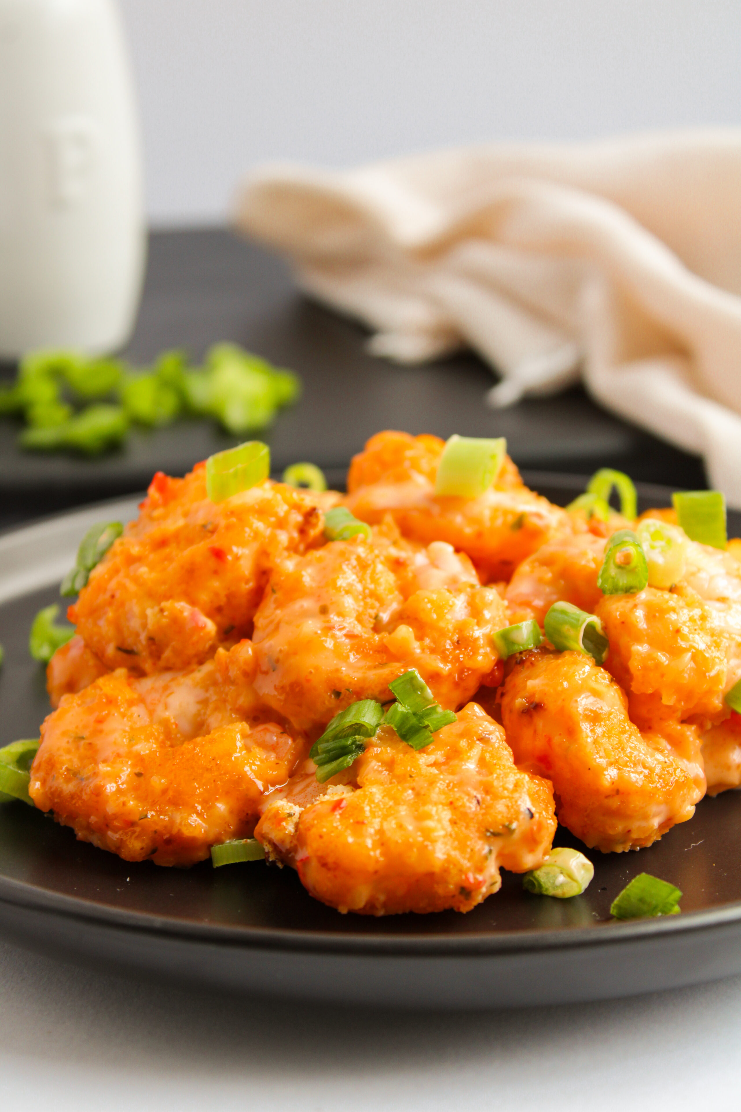 air fried bang bang shrimp on a black dinner plate with rice.