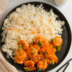 air fryer bang bang shrimp served on a black plate with rice.