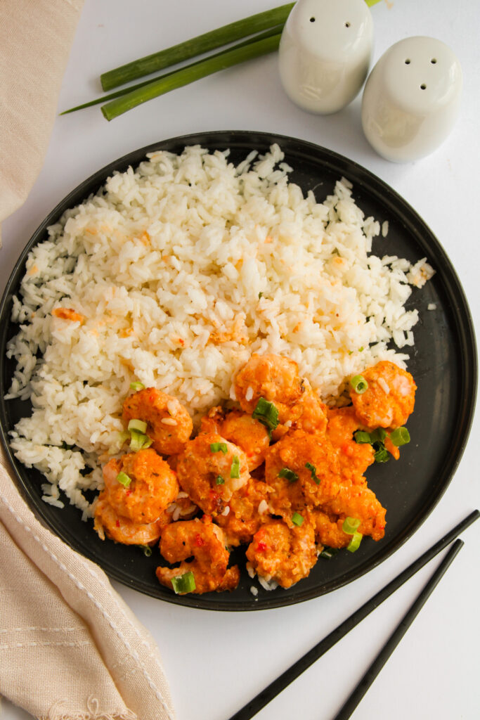 air fryer bang bang shrimp served on a black plate with rice.