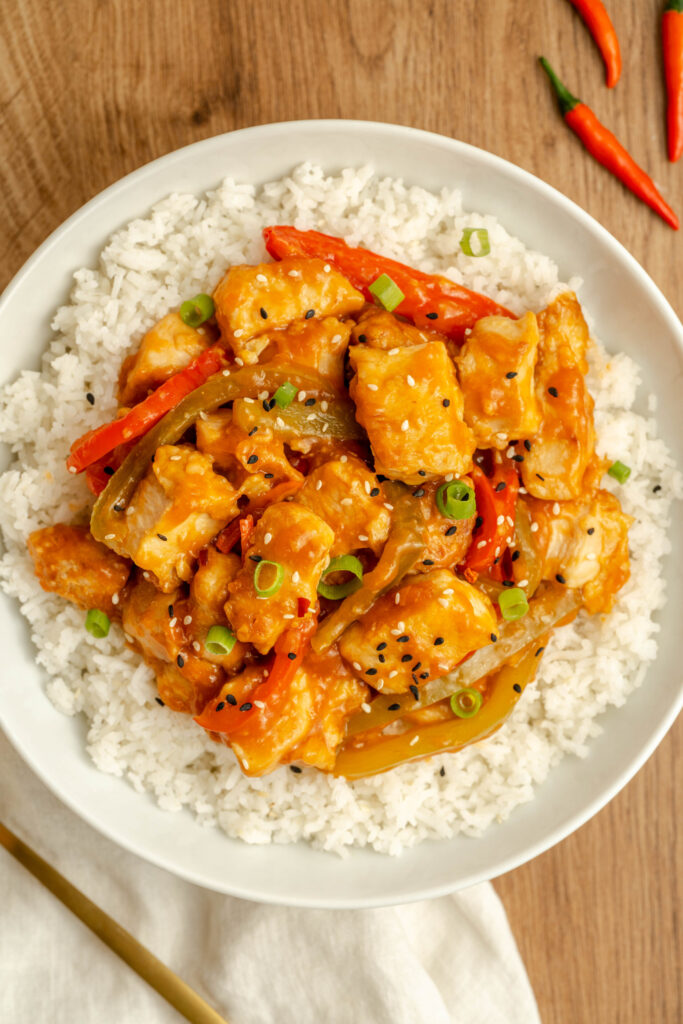 a spicy coated dish in a white bowl with rice.