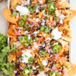 loaded chips with seasoned beef, beans, corn, and toppings.