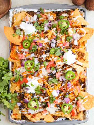 loaded chips with seasoned beef, beans, corn, and toppings.