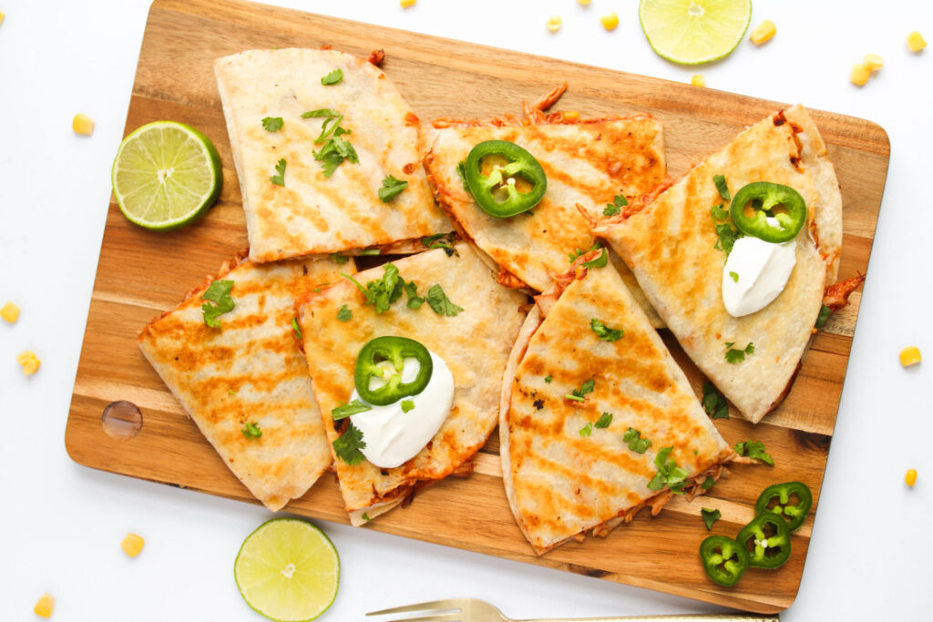 stuffed tortillas toasted and served on a wood cutting board.