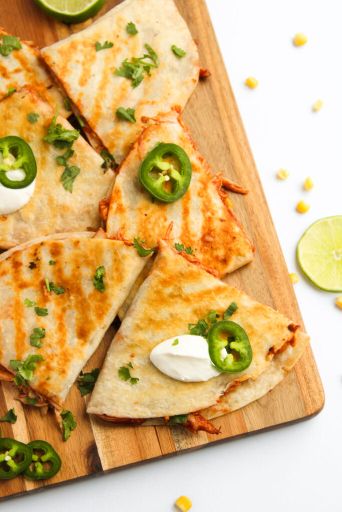 cooked quesadillas topped with jalapenos and sour cream.