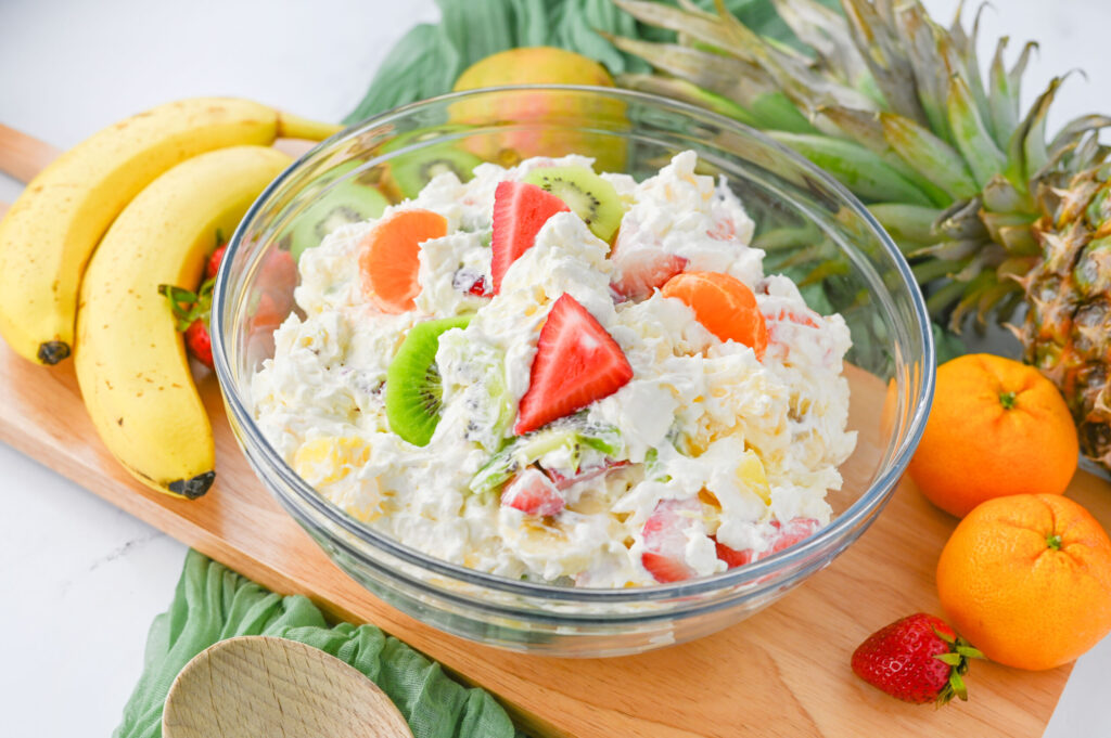 Uma salada de frutas cremosas em uma tigela de vidro.