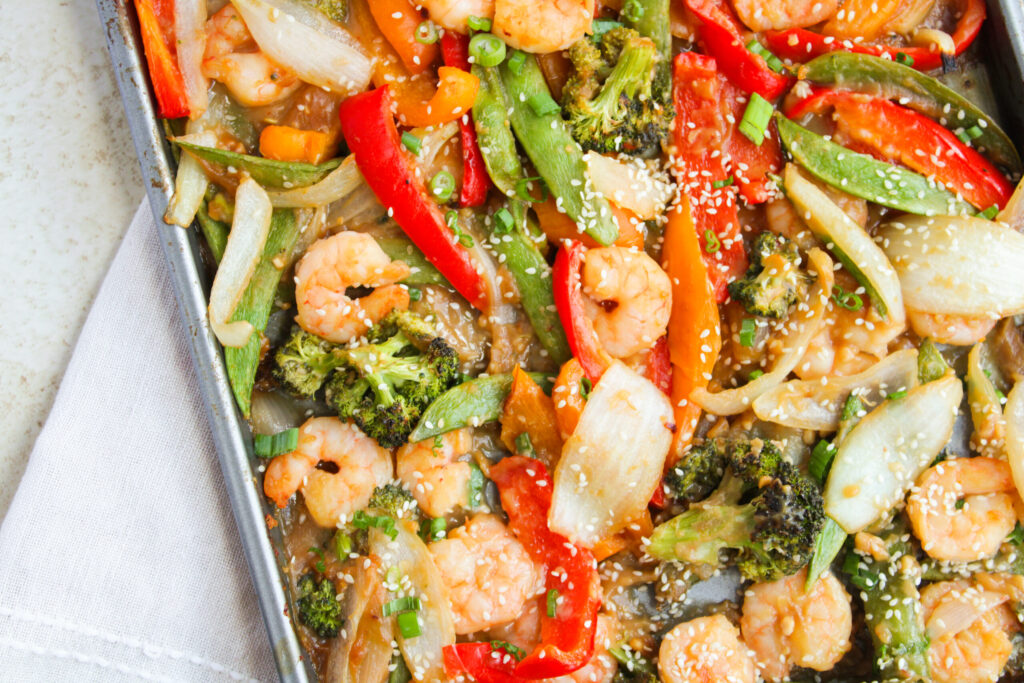 an up close look at fresh vegetables and shrimp cooked in a sauce.