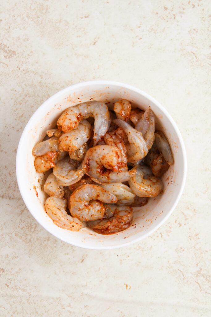 shrimp and seasonings combined in a mixing bowl.