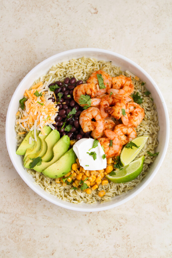 fresh toppings with cooked shrimp and rice in a bowl.