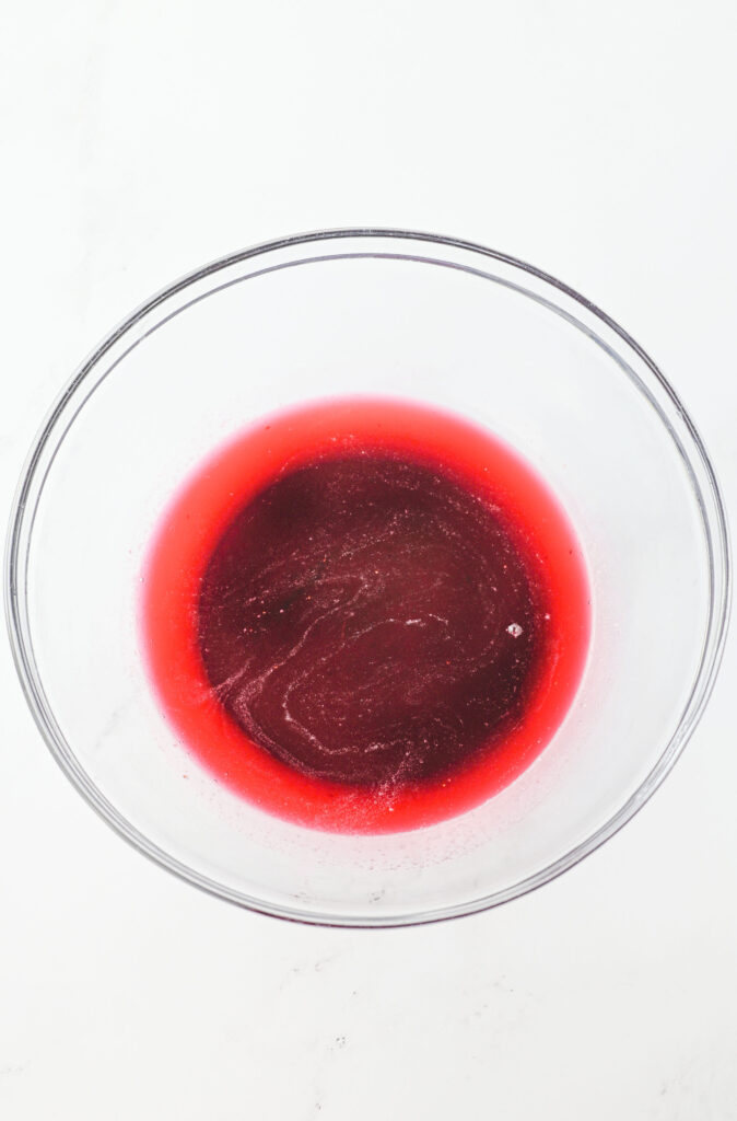 berry syrup strained into a glass bowl.