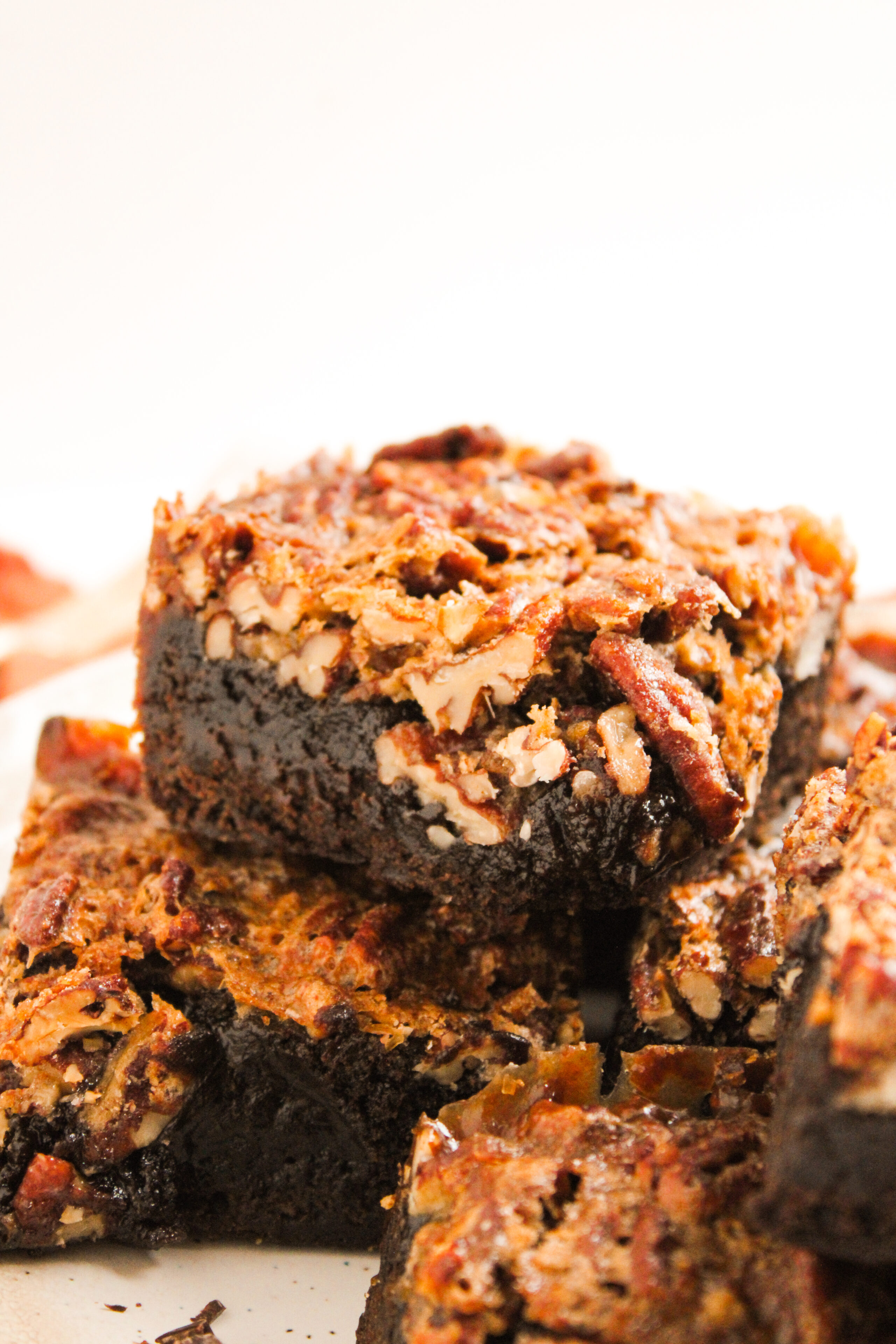 fudge like pecan pie brownies stacked on a plate and ready to serve.