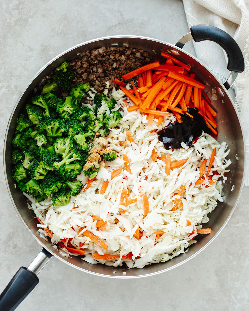 Coleslaw mix and carrots stirred into meat for keto egg roll in a bowl