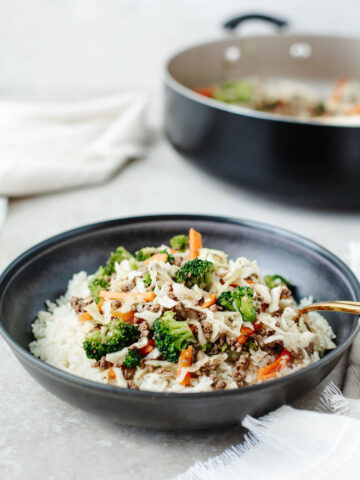 egg roll in a bowl served over white rice in a black bowl.