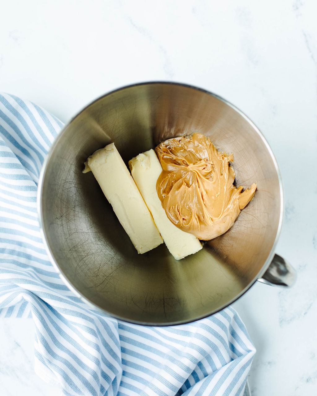 creamy peanut butter and butter being creamed together in a mixing bowl.
