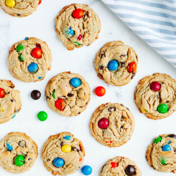 peanut butter m&m cookies on a parchment lined cookie sheet.