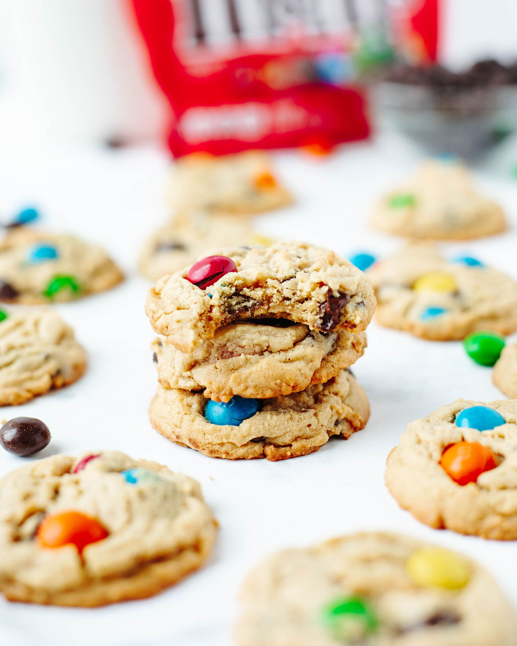 Soft and chewy peanut butter M&M cookies stacked on a piece of parchment paper.