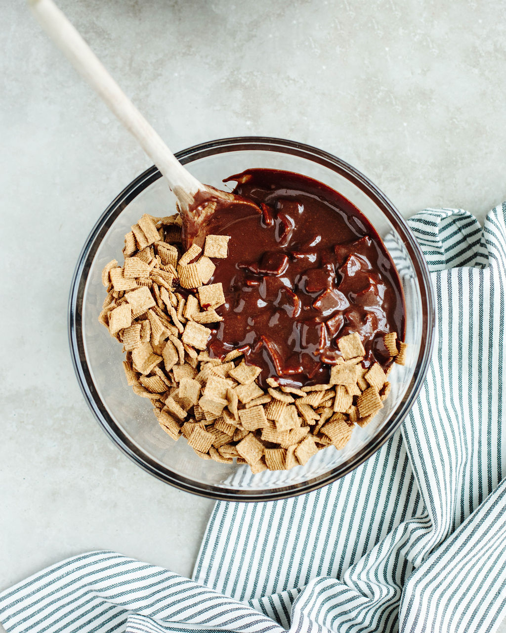 chocolate mixture poured over golden grahams cereal in a glass mixing bowl.