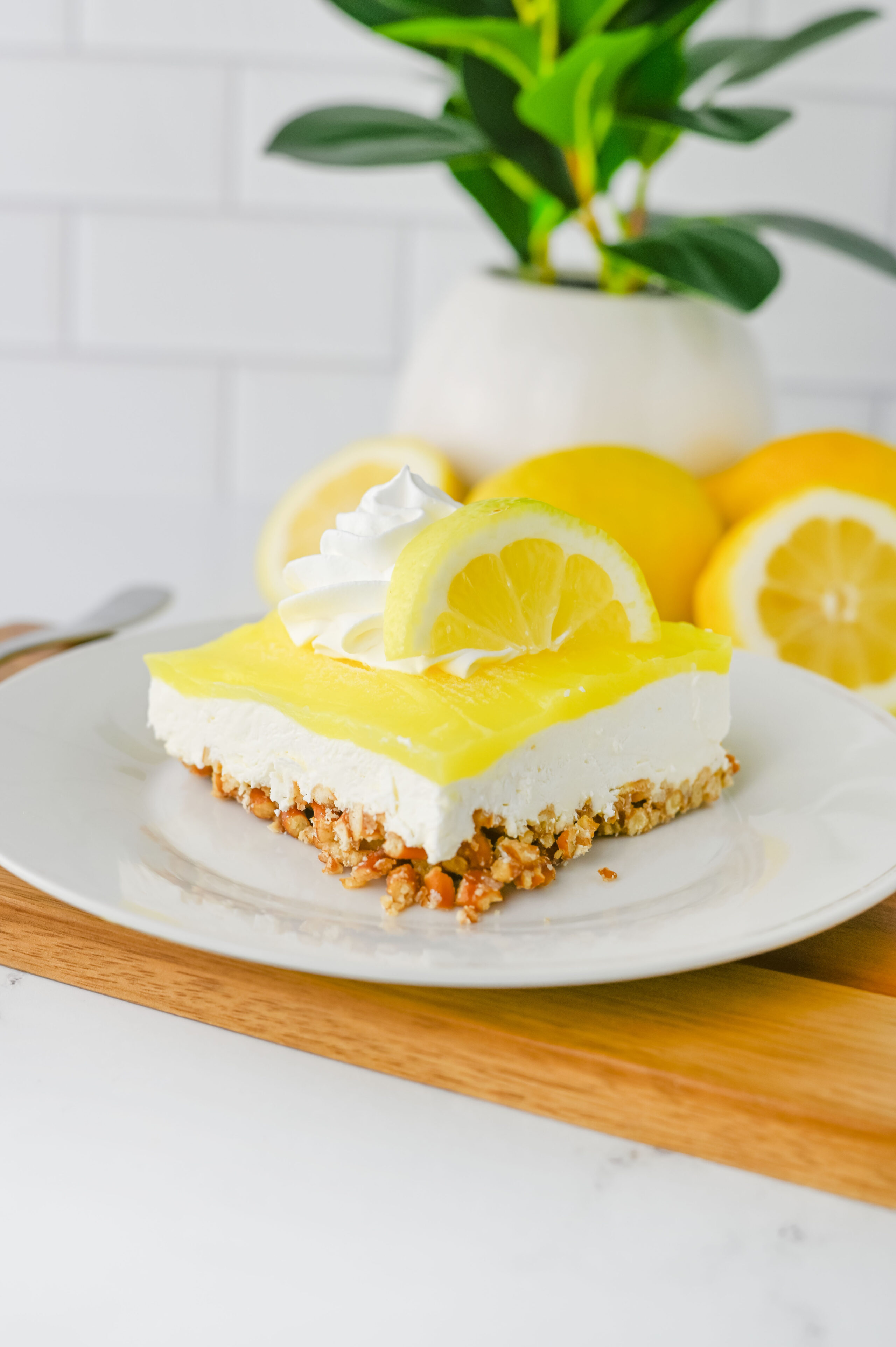 slice of lemon pretzel salad on a white plate with whipped cream.
