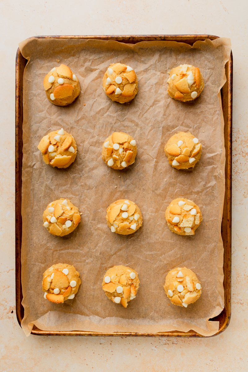 banana pudding cookie dough balls on a parchment lined baking sheet.