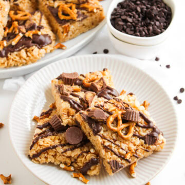 pieces of chocolate peanut butter rice krispie treats on a white plate with chocolate chips.