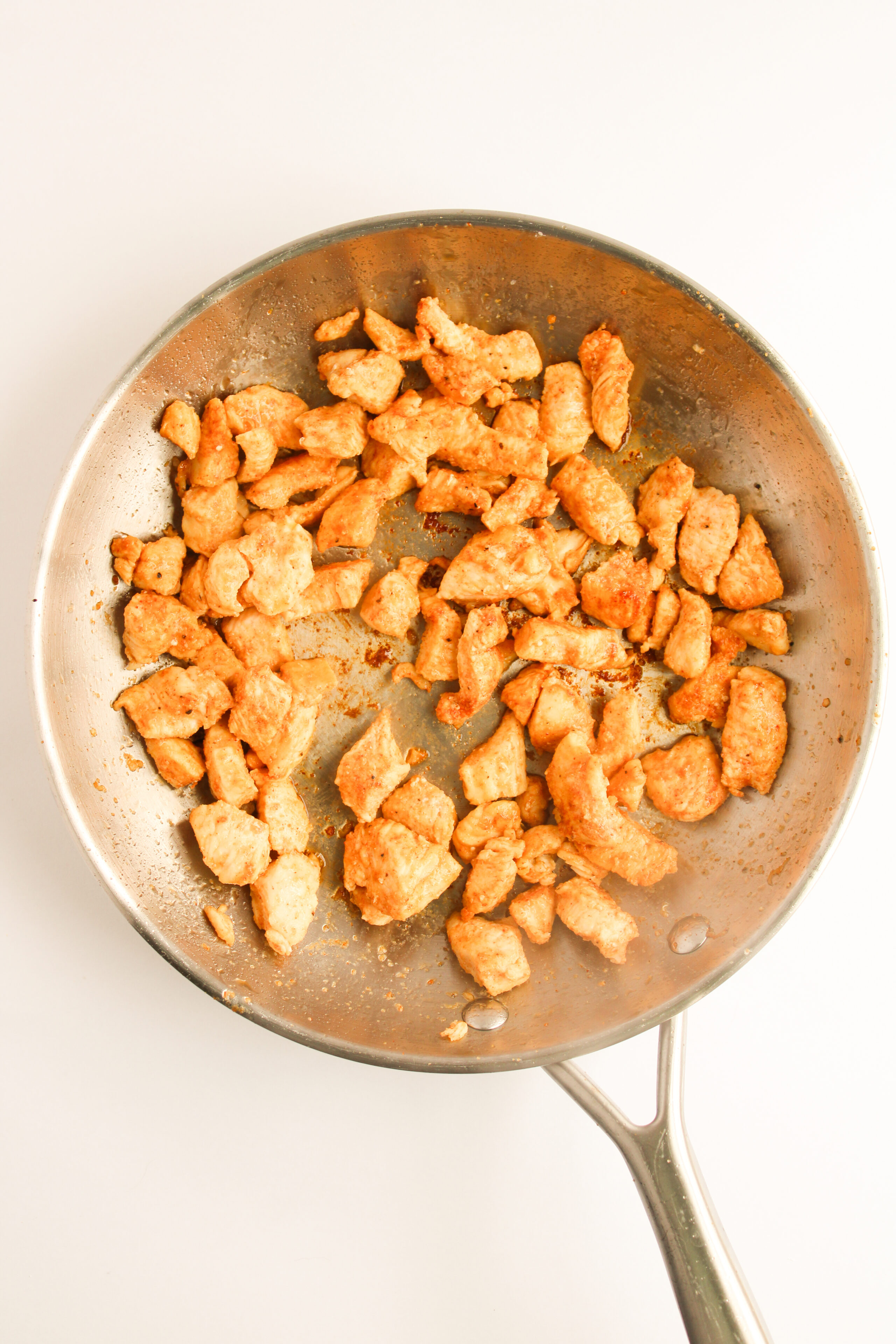 diced seasoned chicken cooked in a skillet.