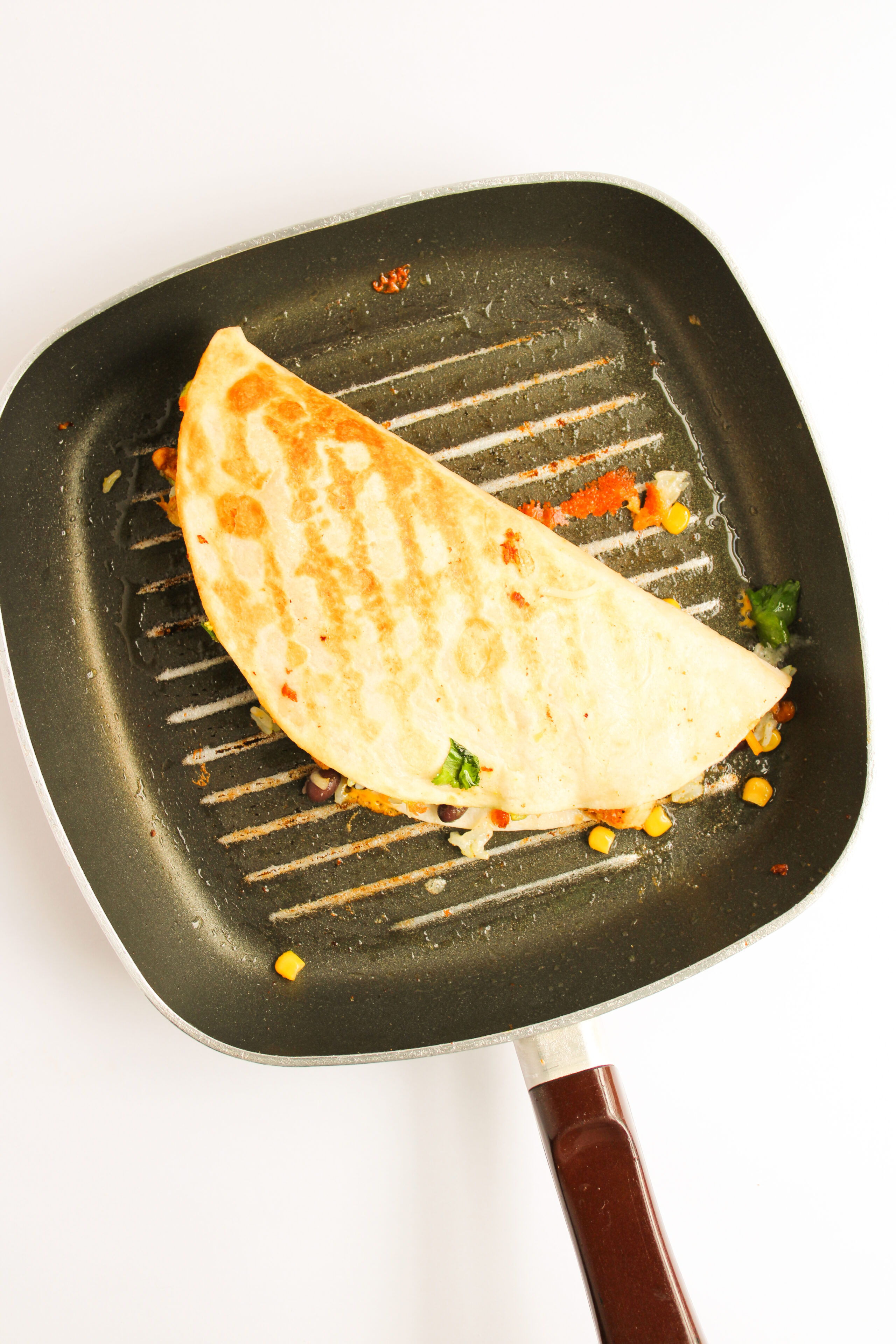 a quesadilla being cooked in a black skillet.