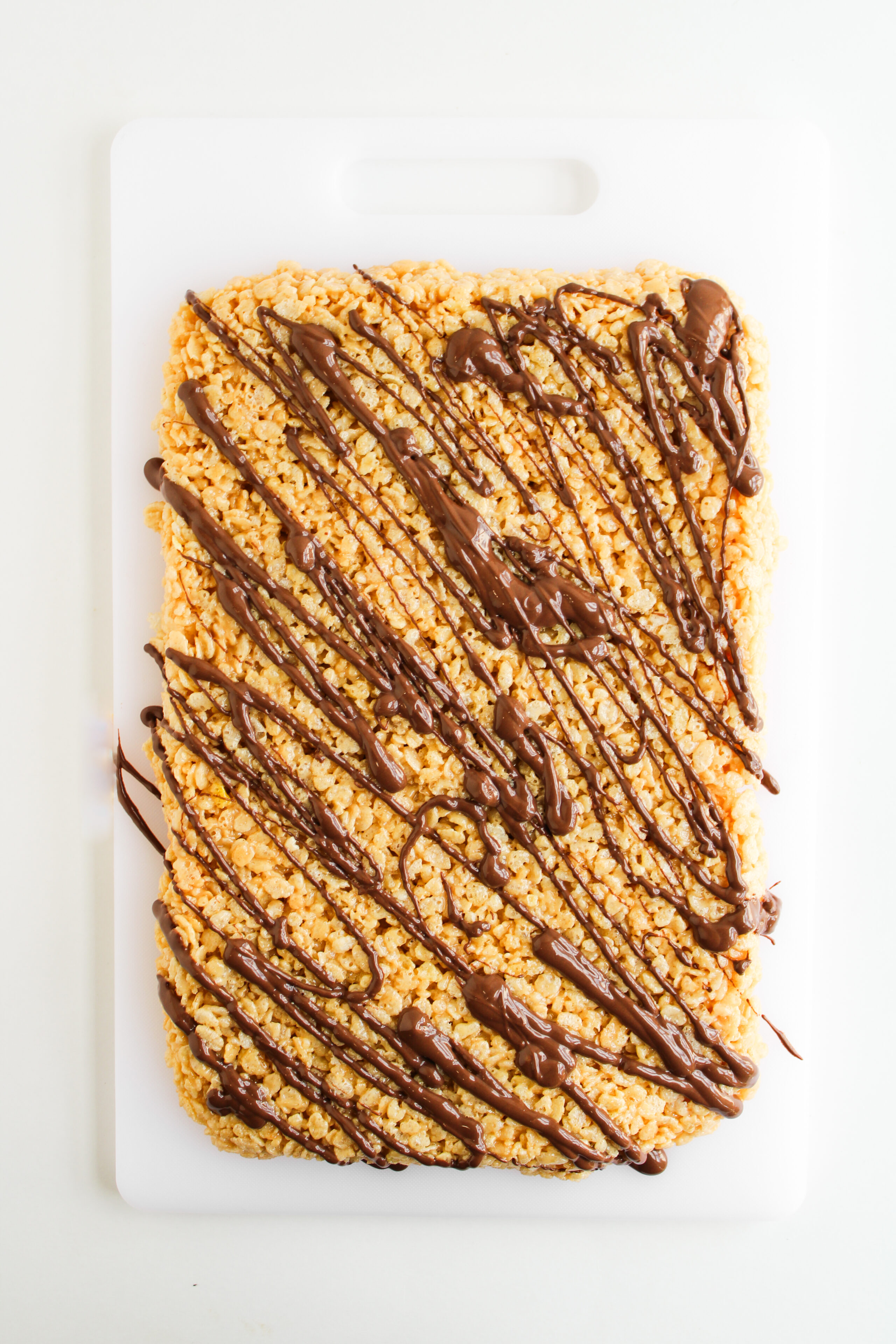 Homemade peanut butter rice krispie bars drizzled with melted chocolate.