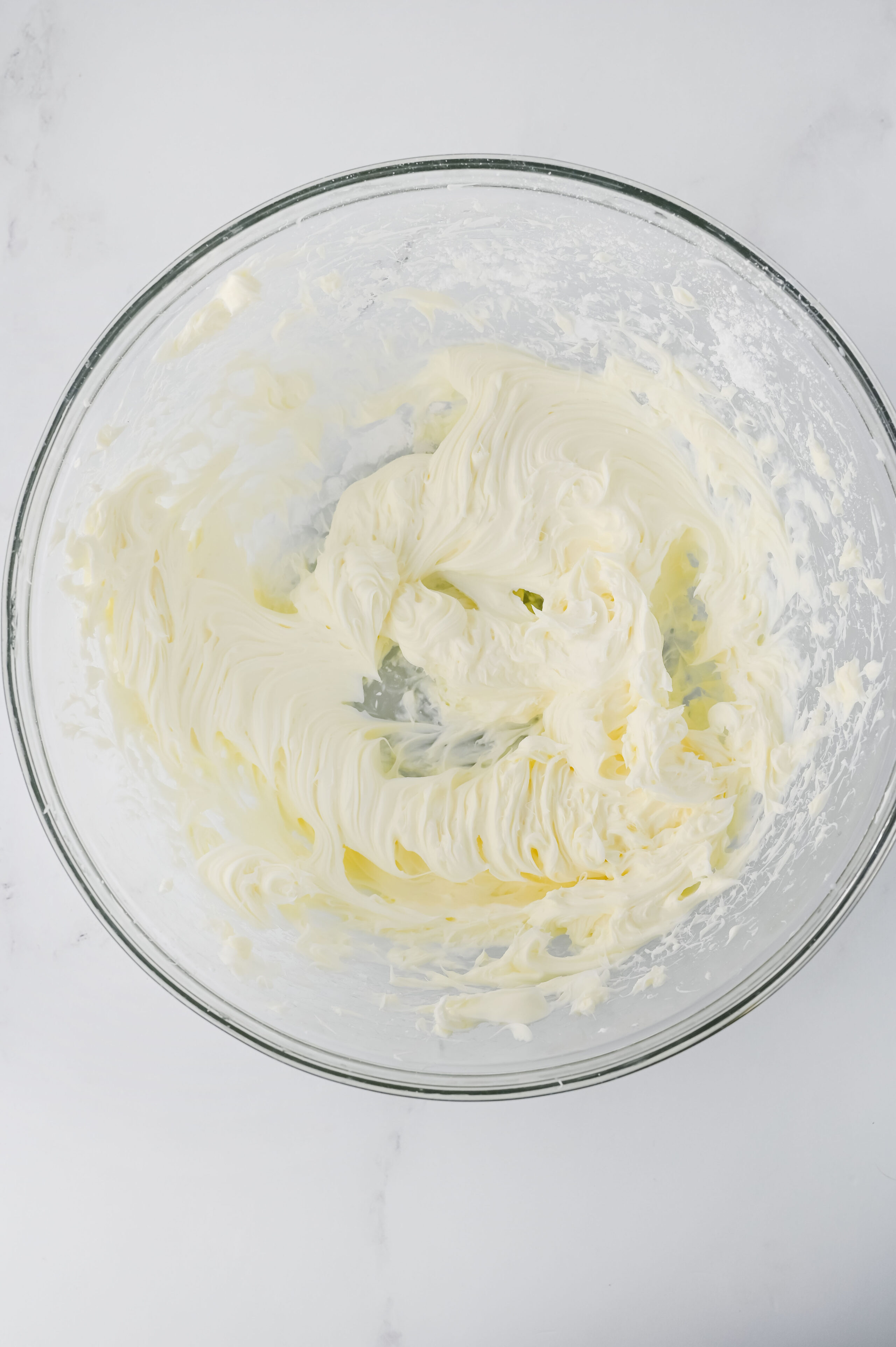 cream cheese and powdered sugar combined in a glass bowl.