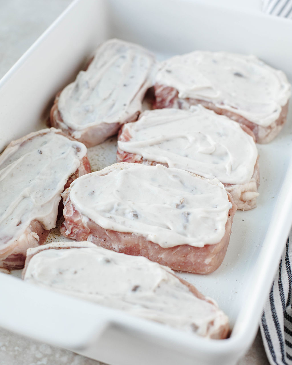 cream of mushroom soup covering pork chops in a baking dish.