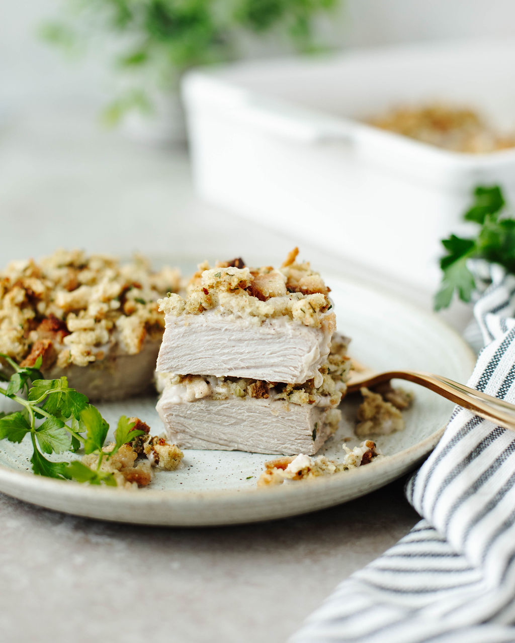 pork chops topped with stuffing and served on a white dinner plate.