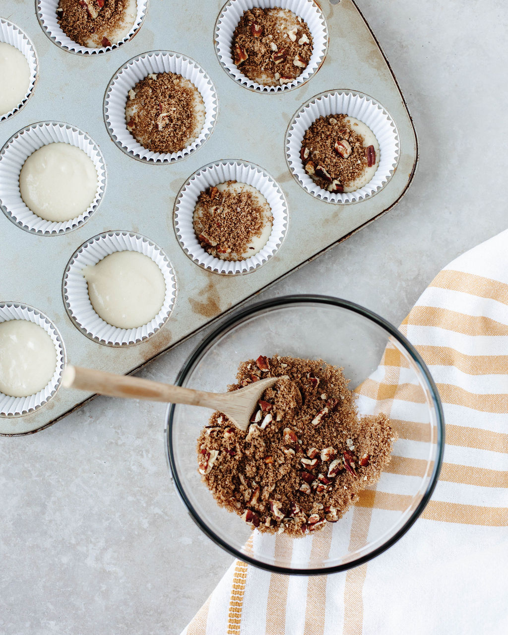 Muffin liners filled with a spoonful of batter and a sprinkle of cinnamon nut streusel.