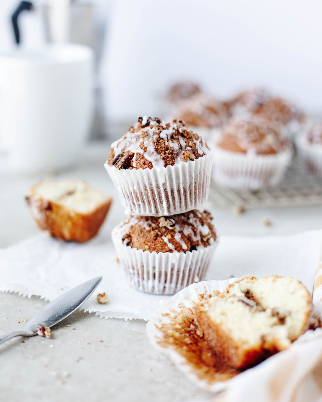 Stacked bakery-style cinnamon crumb muffins with glaze dripping down the sides.