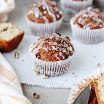 Close-up of a moist coffee cake muffin with crumb topping and vanilla glaze drizzle.