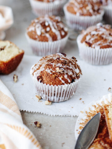 Close-up of a moist coffee cake muffin with crumb topping and vanilla glaze drizzle.