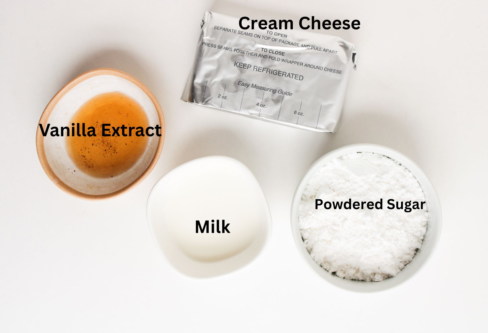 Creamy cream cheese frosting ingredients laid out: cream cheese, butter, powdered sugar, and vanilla extract.