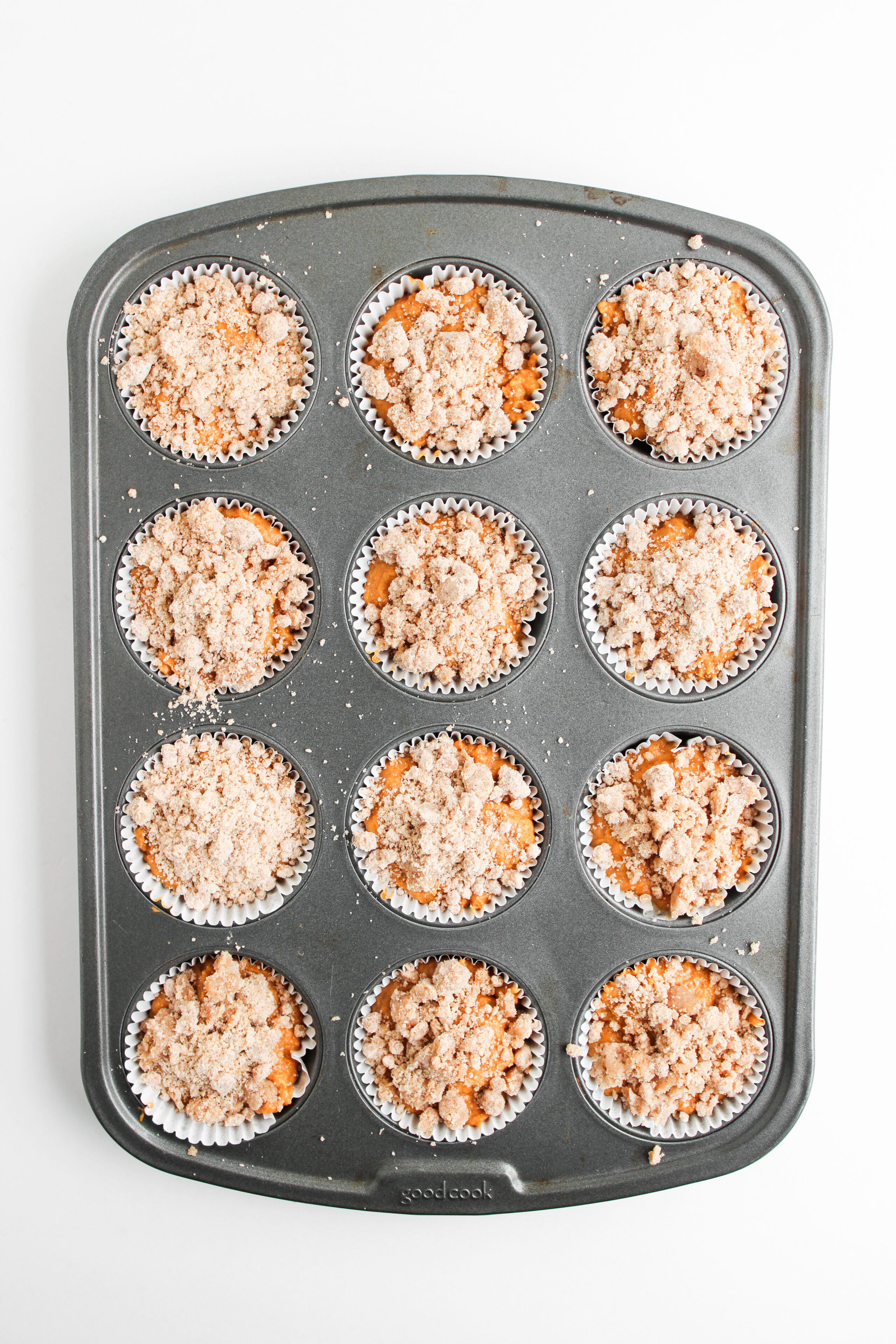 streusel sprinkled on top of muffin batter in a pan.