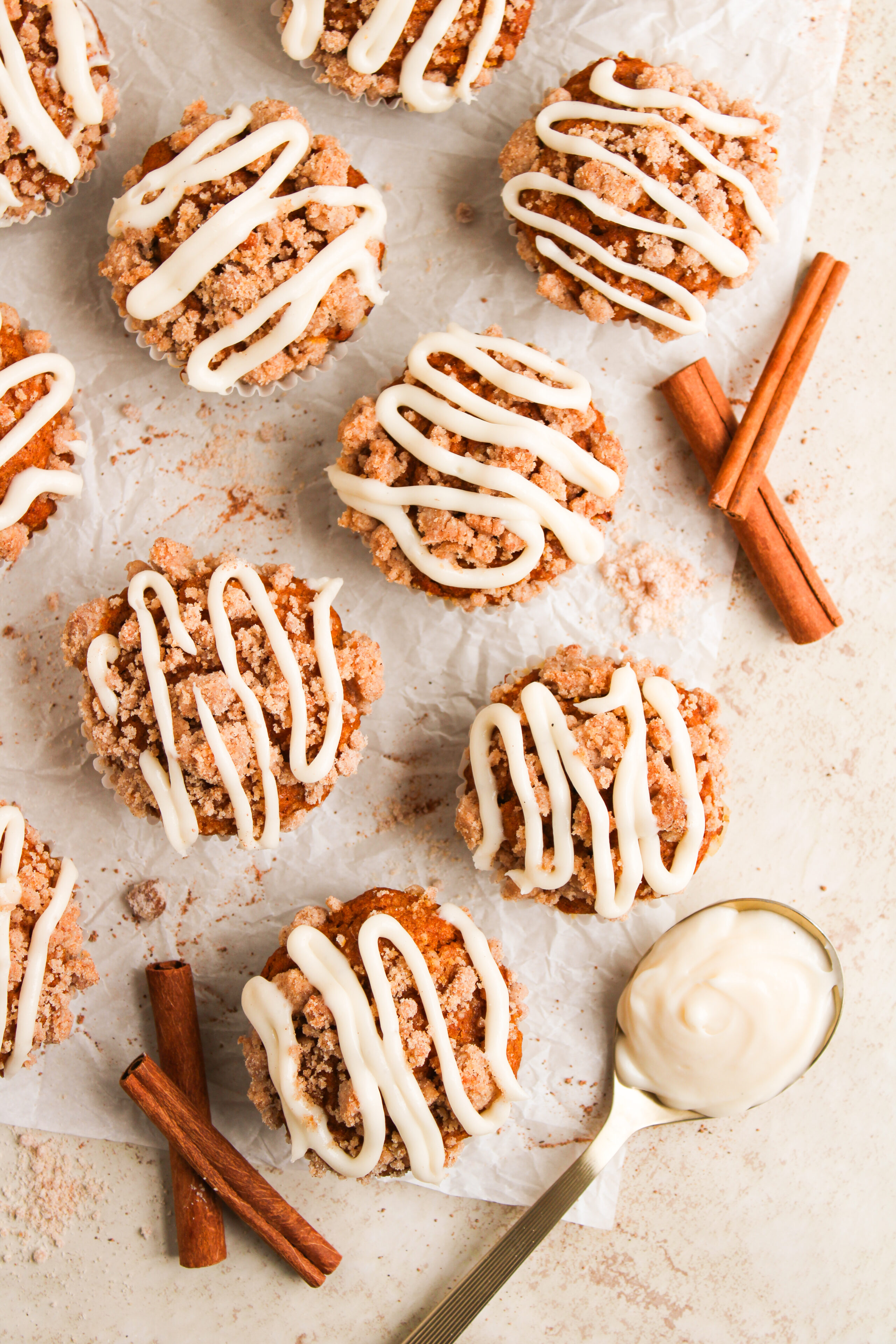 baked pumpkin muffins on parchment paper with drizzled frosting.