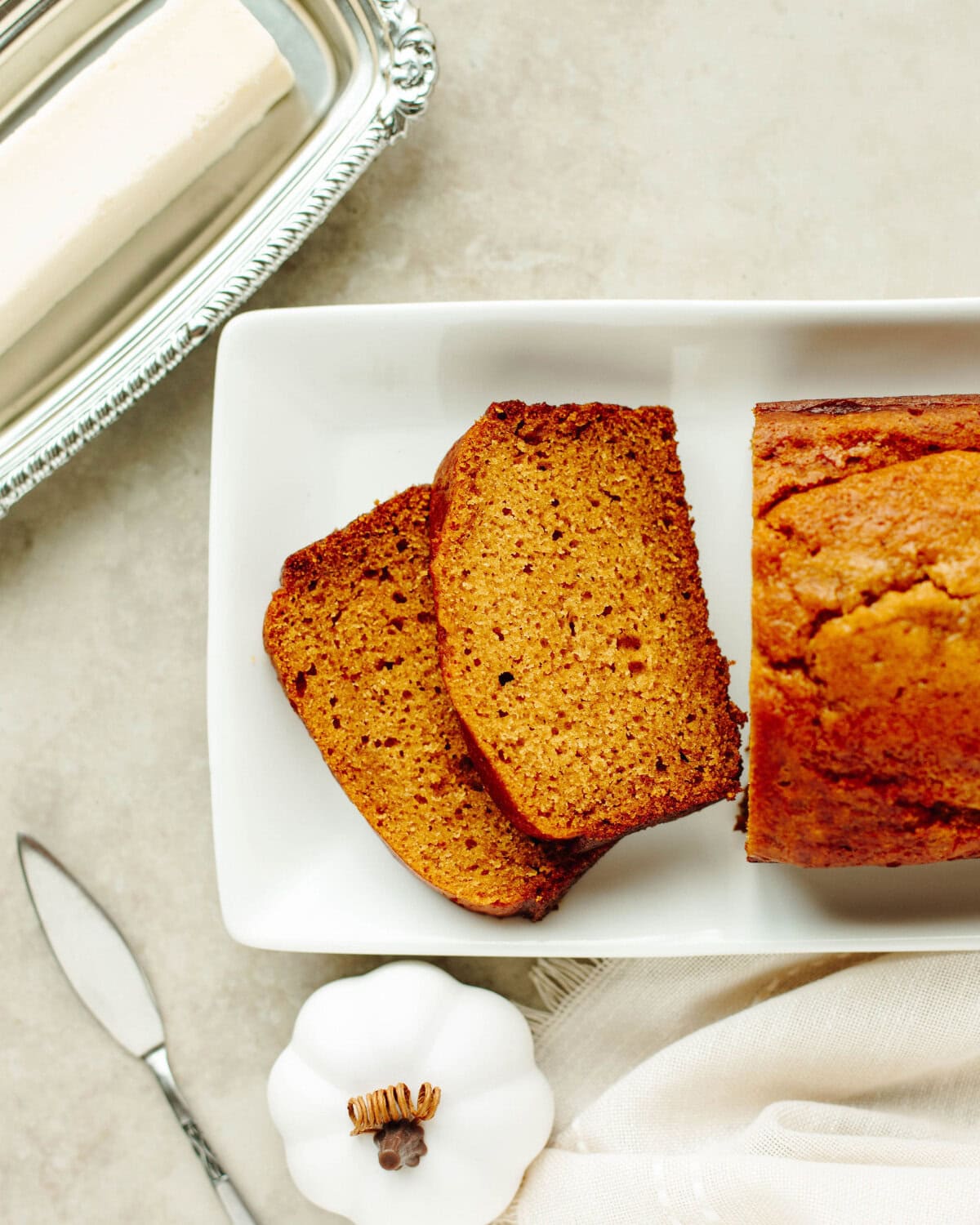 a sliced loaf of pumpkin bread on a white serving tray.