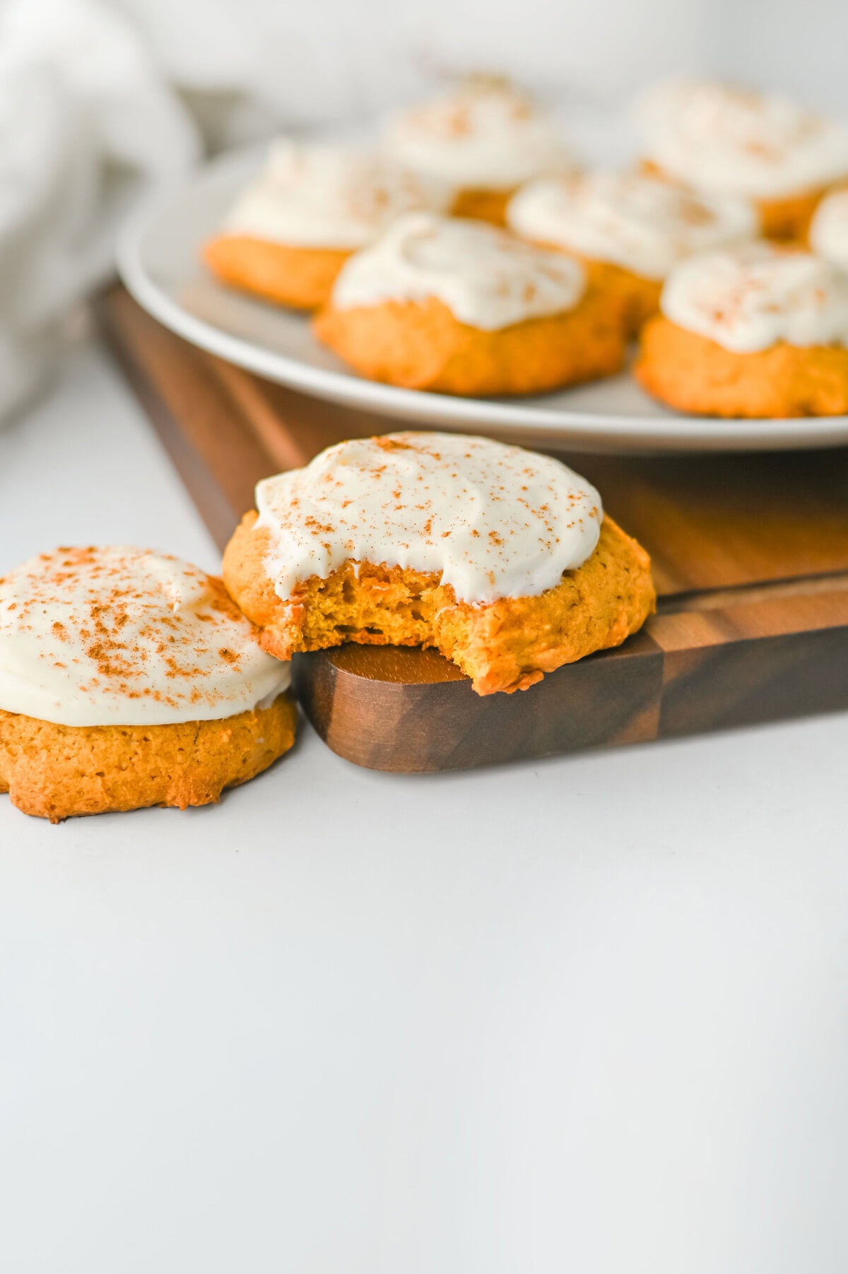 a bite taken out of a pumpkin cookie with cream cheese frosting to show the inside.