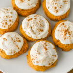 Soft pumpkin cookies with cream cheese frosting on a white plate.