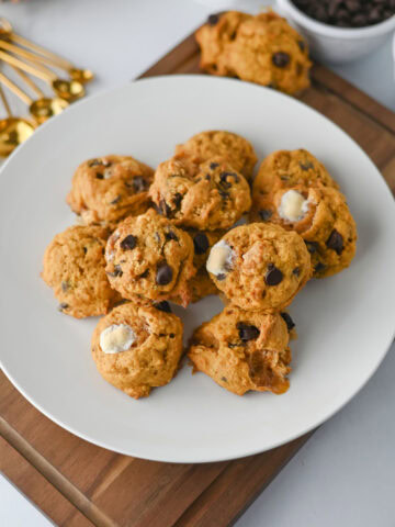 stacked pumpkin smores cookies on a white plate ready to serve.