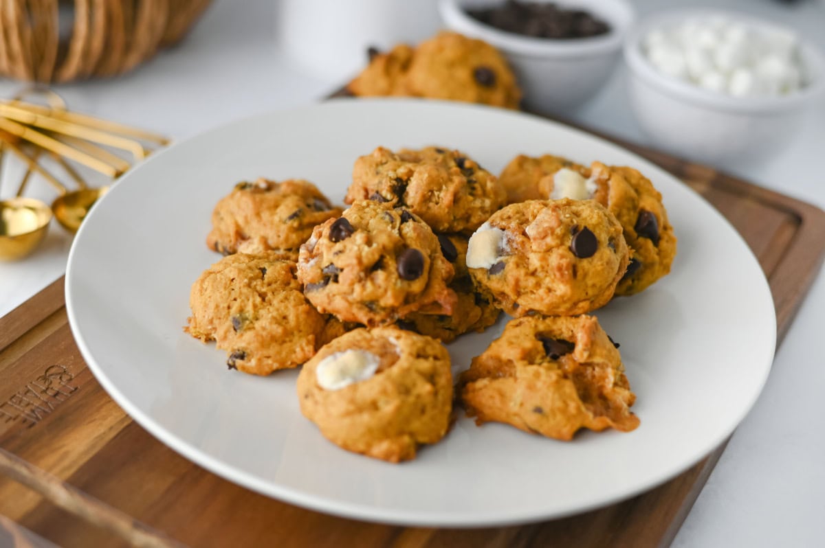 pumpkin cookies with marshmallows, chocolate chips, and graham crackers on a white plate.