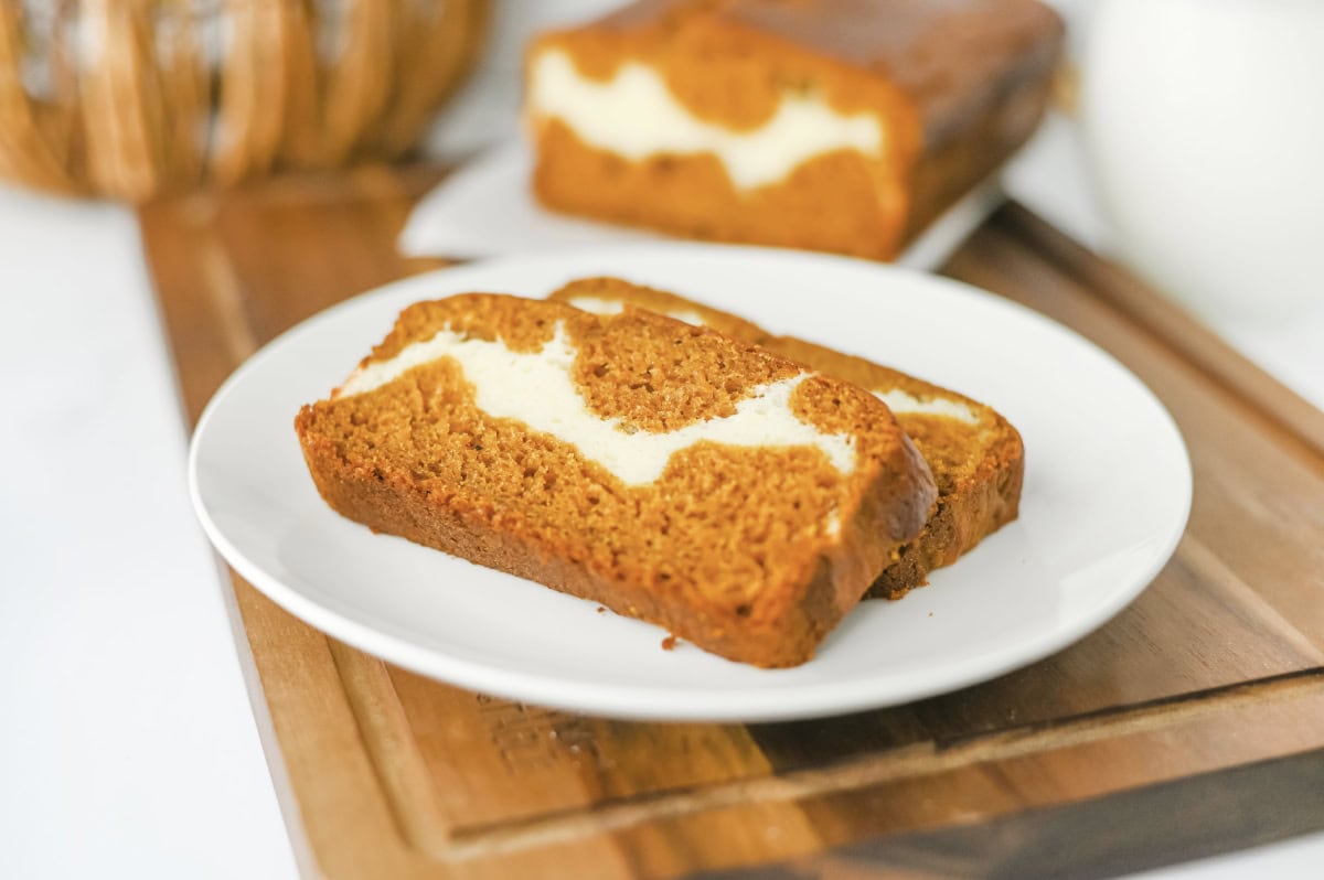 sliced pumpkin cream cheese bread on a white serving plate.