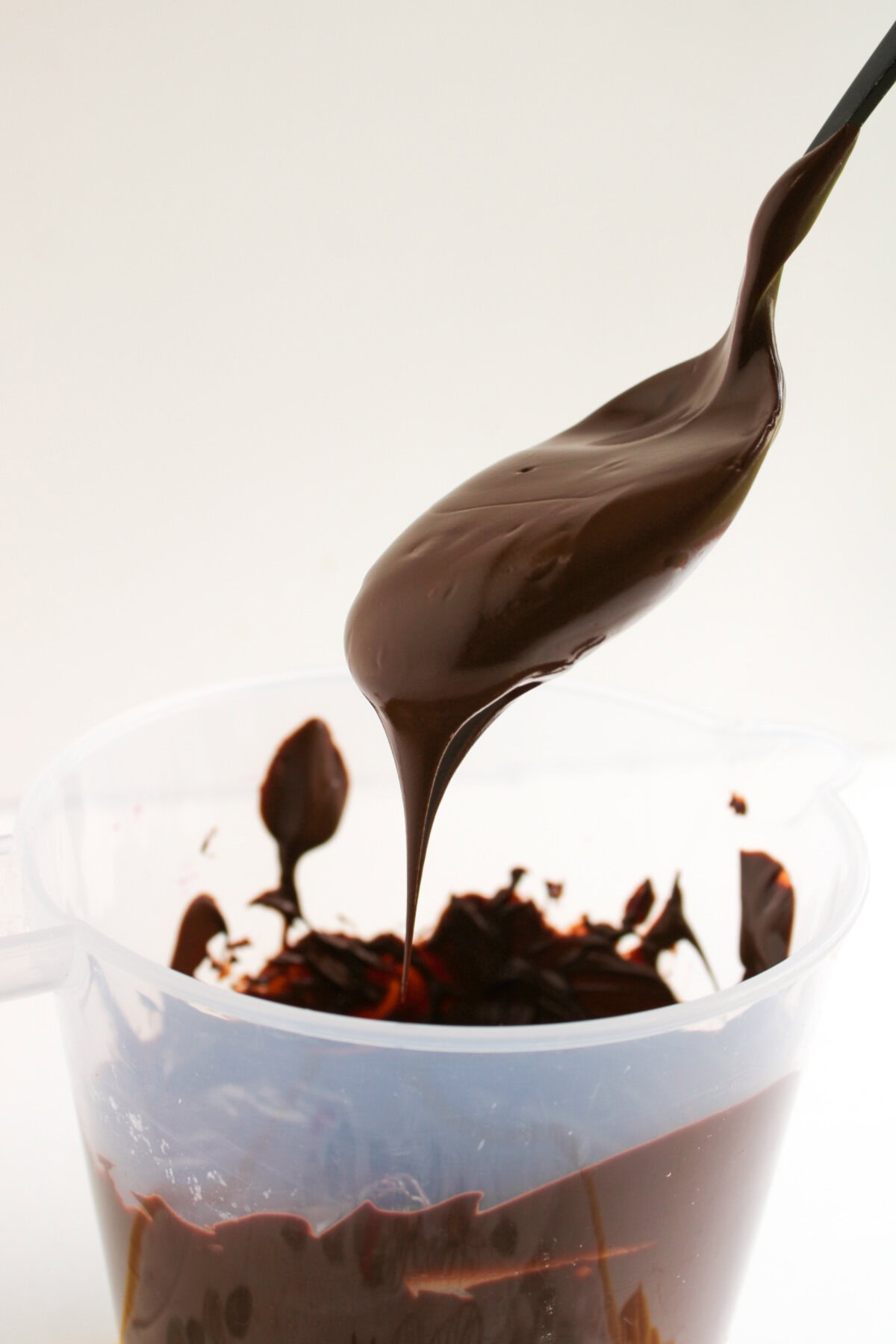 melted chocolate being stirred by a spoon in a bowl.