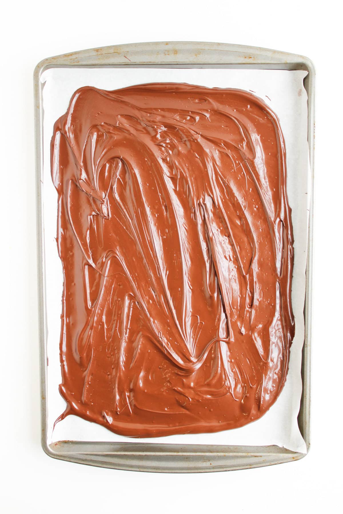 melted chocolate spread on a parchment lined baking sheet.