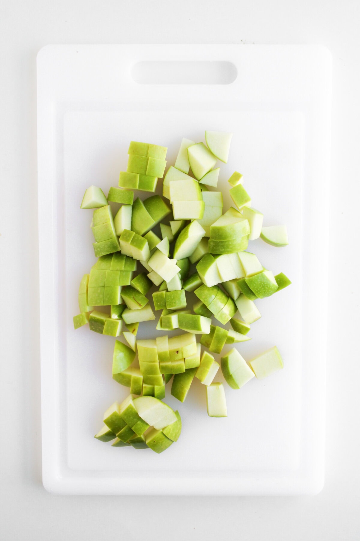 chopped Granny smith apples on a cutting board.