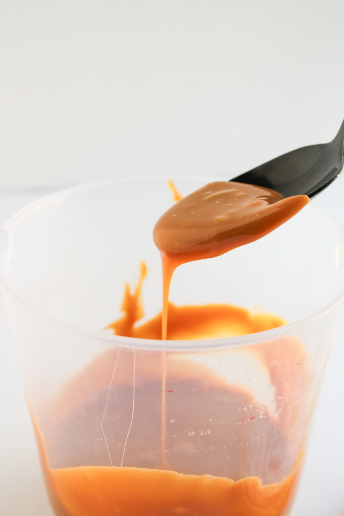melted caramel sauce in a plastic cup with a spoon.