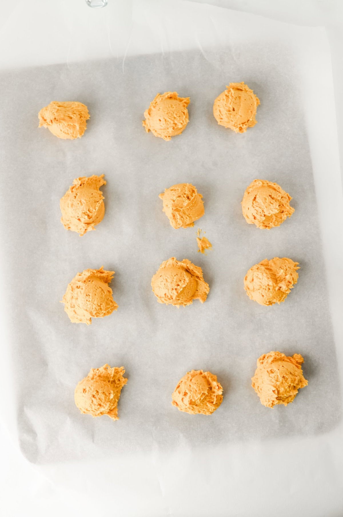 pumpkin cookie dough balls on a parchment lined cookie sheet.