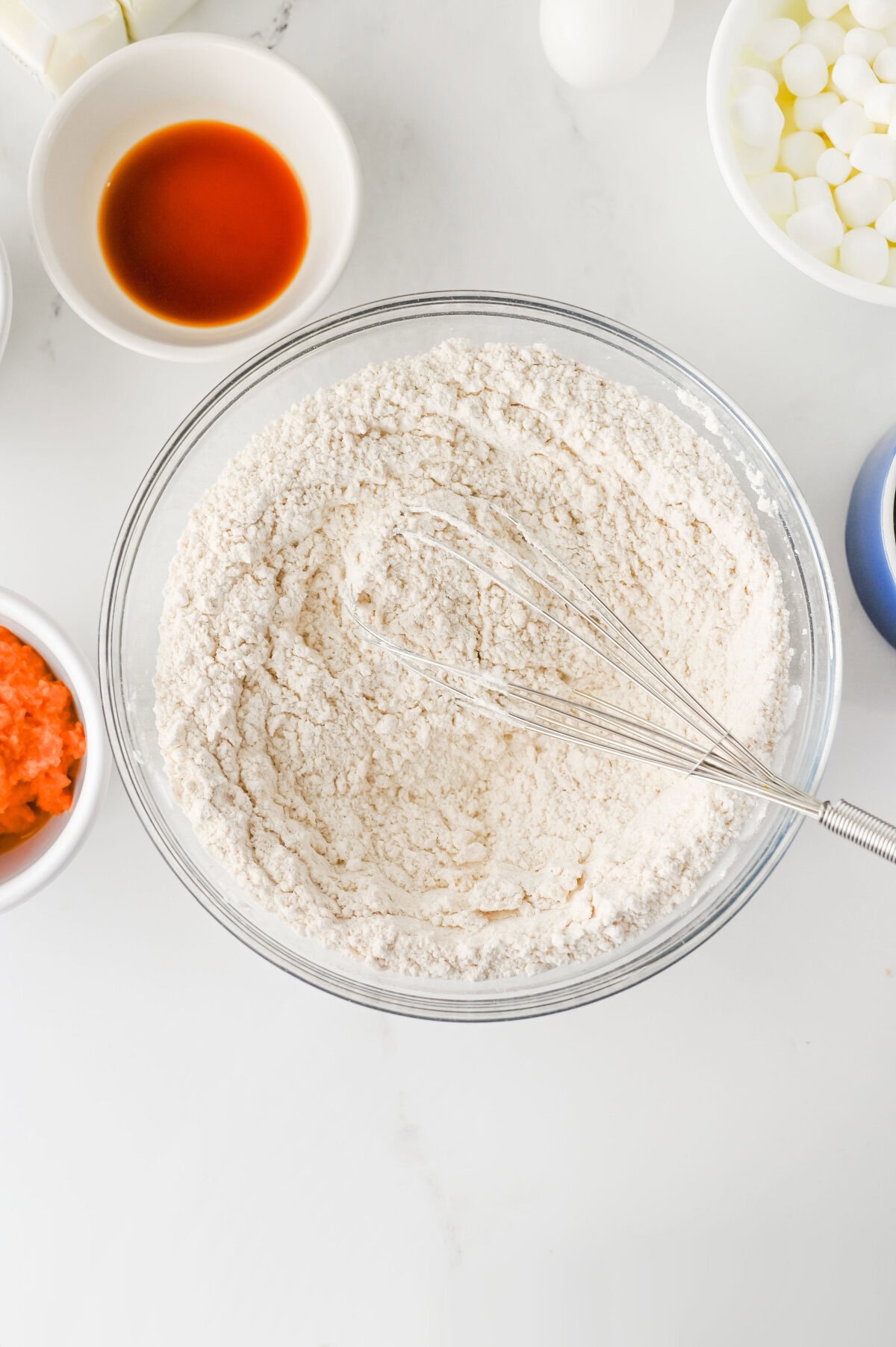 dry ingredients added to a glass mixing bowl to make pumpkin cookies.