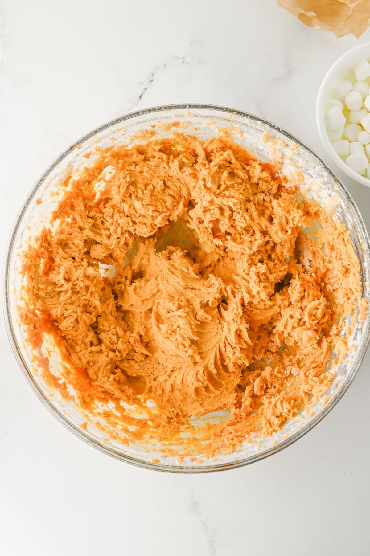 pumpkin cookie dough batter in a glass mixing bowl.