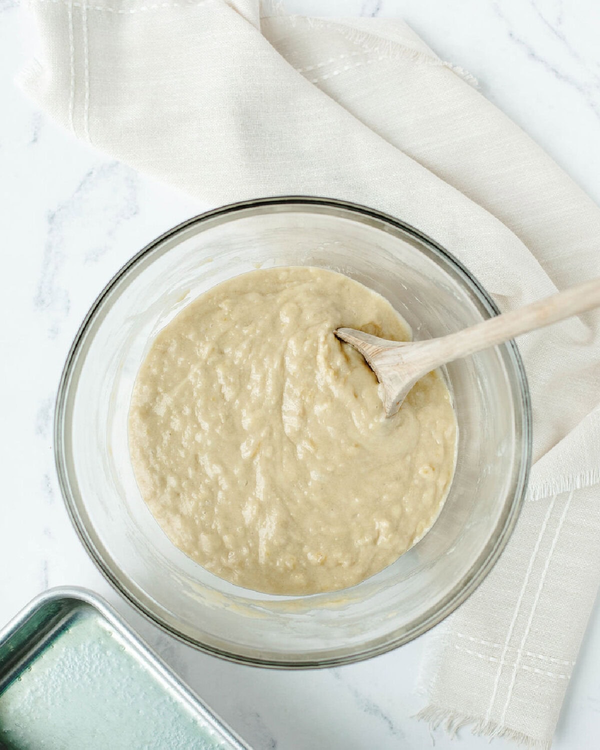 batter mixed together in a glass bowl using a wood spoon.